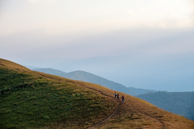 Três mulheres caminhando em uma alta montanha com uma bela natureza cênica e um fundo de céu azul