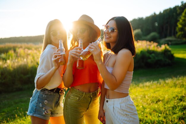 Foto três mulheres descansando na natureza em um piquenique bebendo cerveja comemoram o conceito de amizade de piquenique de férias