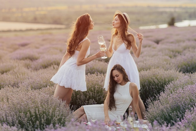 Três mulheres em vestidos brancos em um campo de lavanda