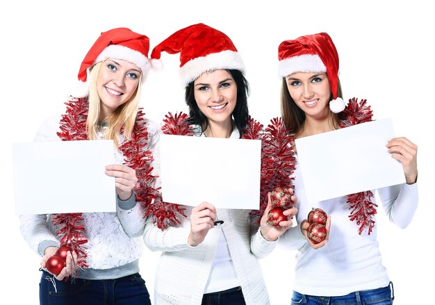 Três mulheres fantasiadas de papai noel com pôsteres em branco