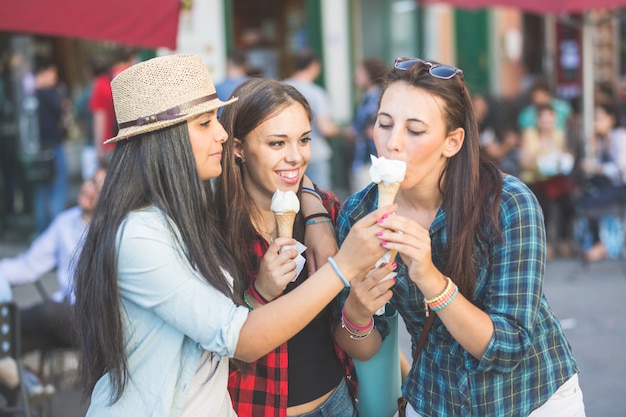 Três mulheres felizes comendo sorvete na cidade