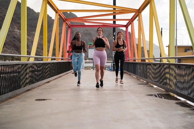 Foto três mulheres jovens a treinar correndo juntas perto da praia conceito de motivação para exercícios desportivos
