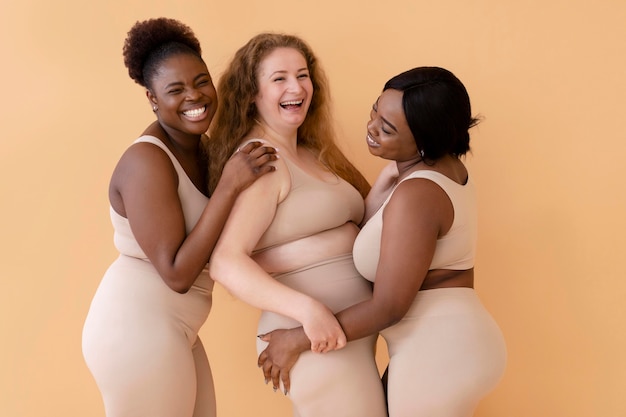 Três mulheres sorridentes em shapers de corpo nu posando juntas