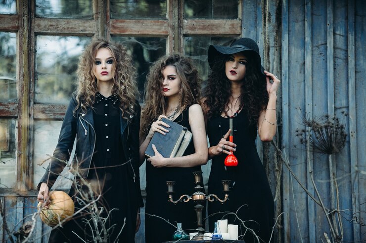 Foto três mulheres vintage como bruxas em poses perto de um prédio abandonado na véspera do halloween