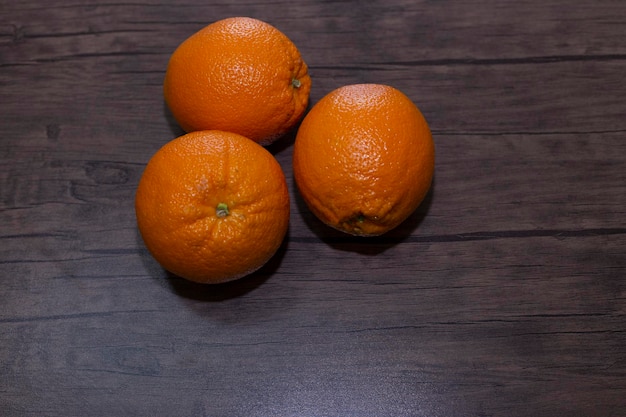 tres naranjas en un fondo de madera