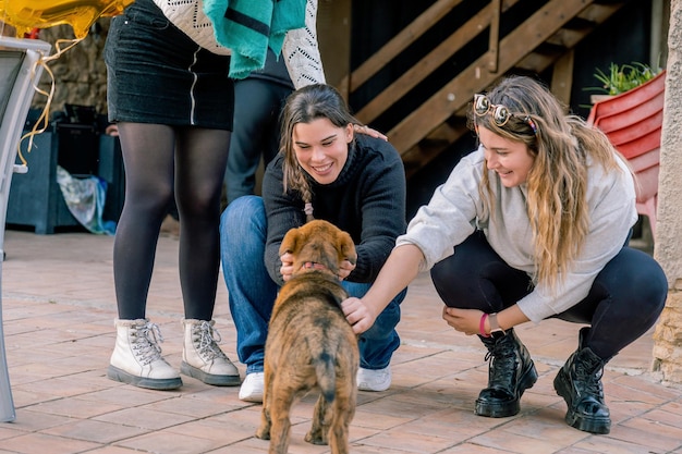 Foto tres niñas acarician a un cachorro de perro pastor fuera de una granja concepto de animalismo