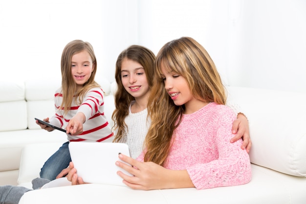 Tres niñas de amigos de hermana de niño jugando juntos con tablet pc