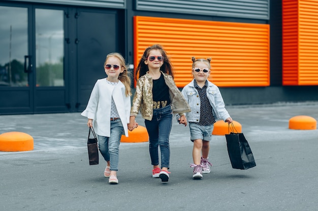 Tres niñas de moda con bolsas caminando de la tienda.