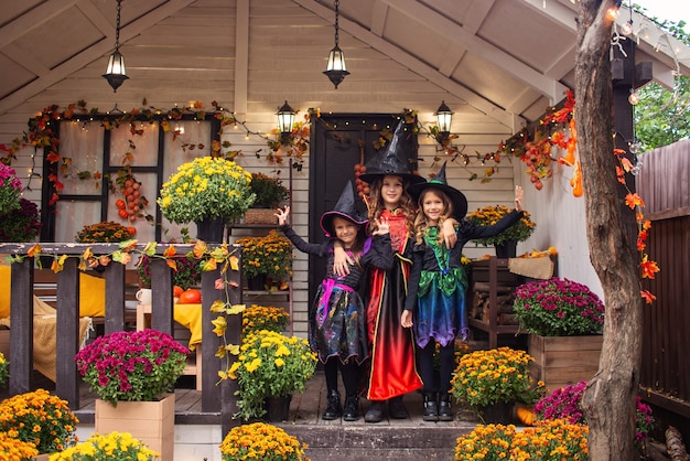 Tres niñas vestidas con disfraces de brujas celebran la divertida fiesta de Halloween