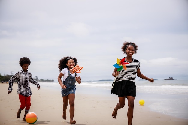 Tres niños afroamericanos divirtiéndose en una playa tropical Concepto étnicamente diverso