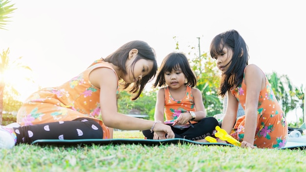 Tres niños asiáticos jugando en el parque con fondo de puesta de sol