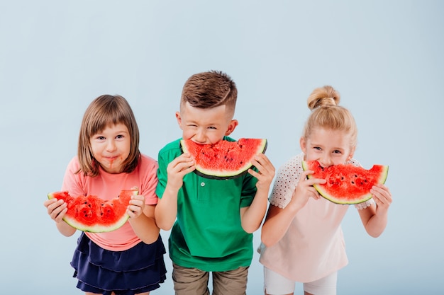 Tres niños comiendo rodajas de sandía