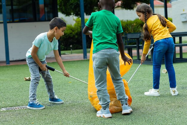 Tres niños están recogiendo basura en la escuela.