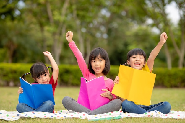 Tres niños leyendo en el parque.