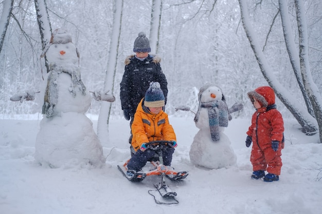 Tres niños de la misma familia en un paseo por Winter Park y dos divertidos muñecos de nieve