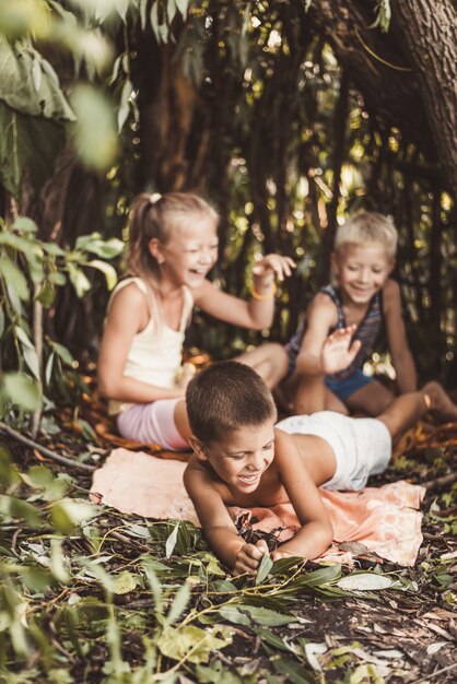 Tres niños del pueblo juegan en una choza que ellos mismos han construido con hojas y ramitas.