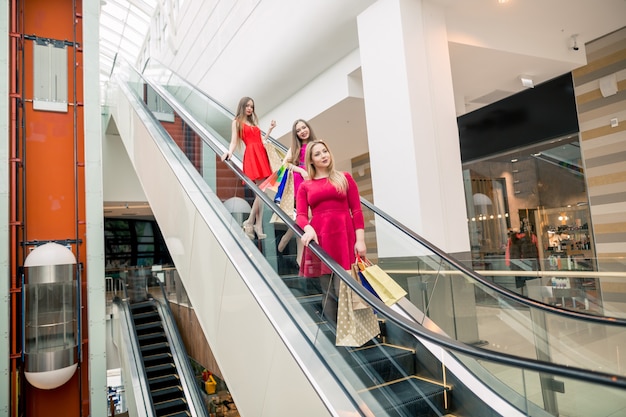 Tres novias en escaleras mecánicas con bolsas de compras