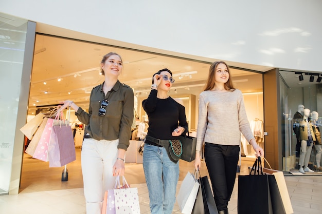 Tres novias glamorosas con bolsas de papel de compras caminando