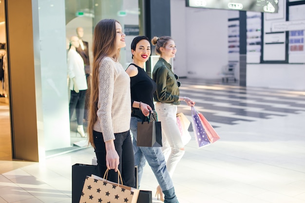 Tres novias glamorosas con bolsas de papel de compras caminando