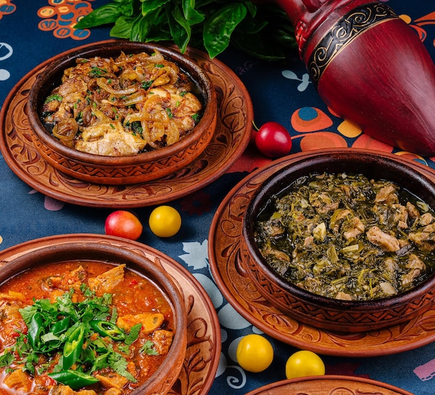 Tres ollas de barro llenas de deliciosa comida de la cocina georgiana de pie en una mesa