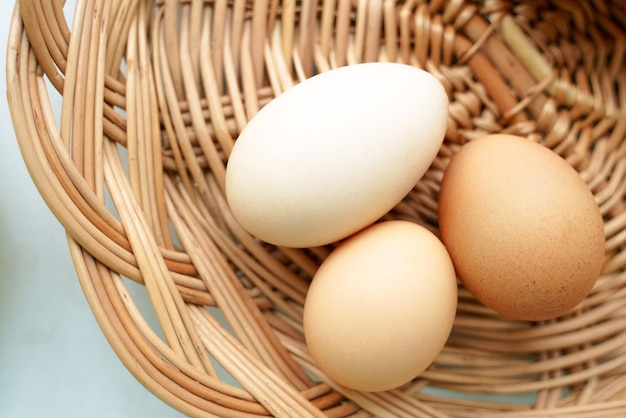 Foto três ovos de galinha de cores diferentes e tamanhos diferentes estão em uma cesta de vime