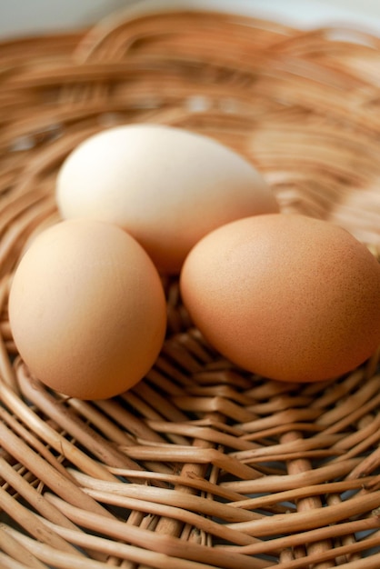 Foto três ovos de galinha de cores diferentes e tamanhos diferentes estão em uma cesta de vime