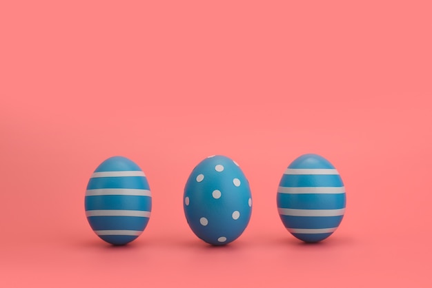 Três ovos decorados de azul em uma fileira com listras e círculos brancos. Copie o espaço