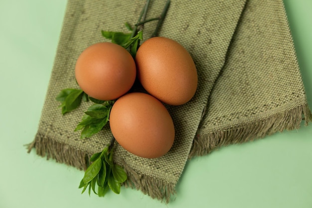 três ovos em guardanapos e decoração de galhos com folhas