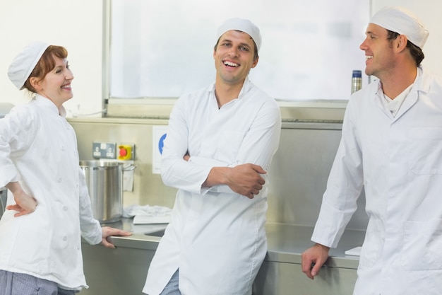 Tres panaderos charlando de pie en una panadería