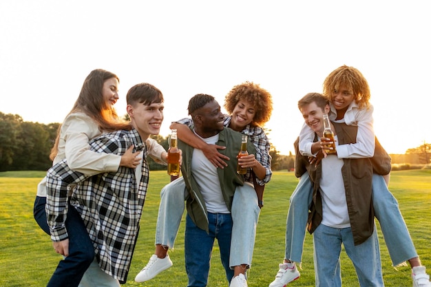 tres parejas de jóvenes multirraciales bebiendo cerveza y celebrando un brindis en una fiesta en el parque