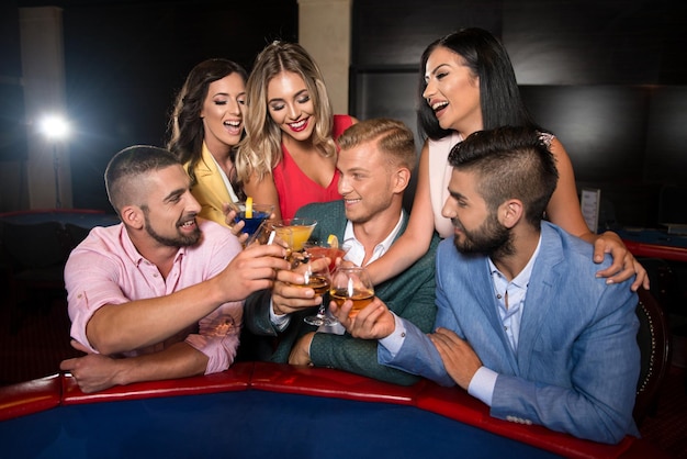 Tres parejas de moda detrás de la mesa en un casino