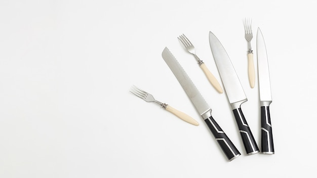 Tres pares de cuchillos de cocina, tenedores con mangos negros. fondo blanco flatlay