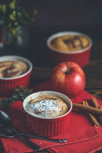 Tres pasteles de manzana en moldes de cerámica con servilleta roja ramekin en una mesa de madera oscura Cerca de la profundidad poco profunda del campo