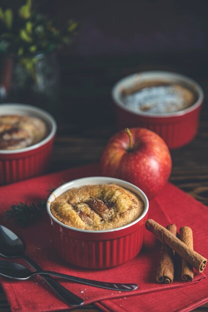 Tres pasteles de manzana en moldes de cerámica con servilleta roja ramekin en una mesa de madera oscura Cerca de la profundidad poco profunda del campo