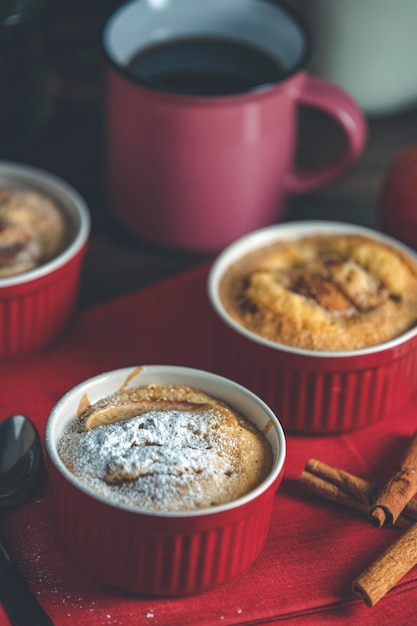 Tres pasteles de manzana en moldes de cerámica con servilleta roja ramekin en una mesa de madera oscura Profundidad poco profunda del campo