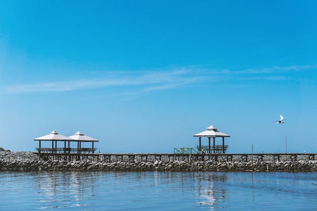 Três pavilhões estão localizados no rio rochoso e o céu azul é brilhante.