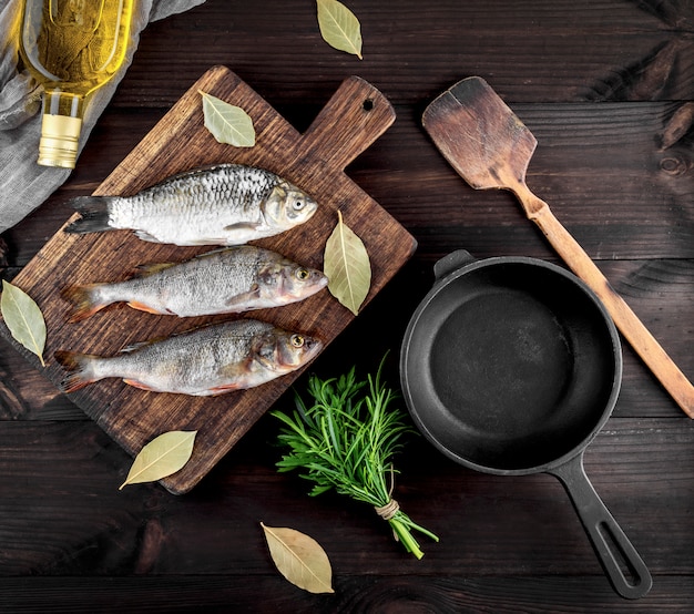 Tres peces de río en una tabla de madera marrón y una sartén de hierro fundido negro