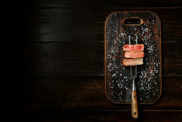 Três pedaços de carne em um garfo para carne. três tipos de carne assada, rara, média e bem passada.