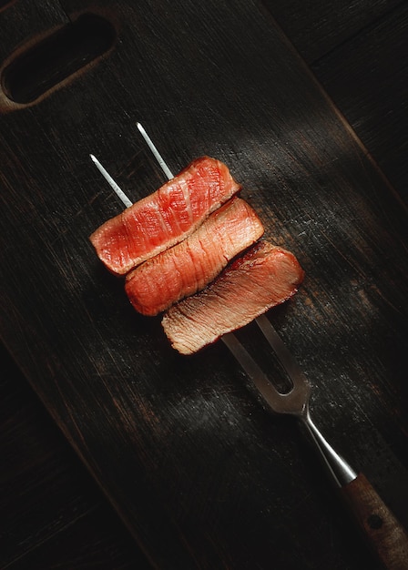 Três pedaços de carne em um garfo para carne três tipos de carne assando mal passado bem feito