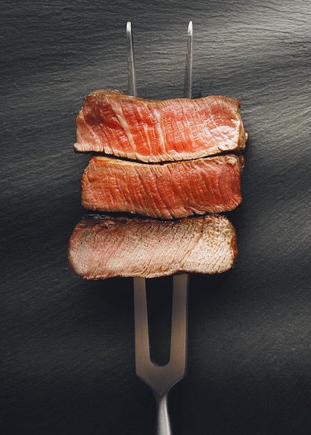 Três pedaços de carne em um garfo para carne três tipos de carne assando mal passado bem feito