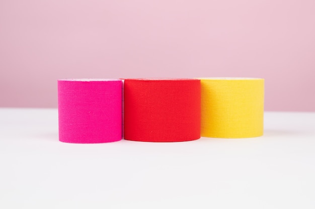 Três pedaços de fita adesiva de levantamento ou kinesio rola em fundo rosa com espaço de cópia. Conceito de medicina alternativa.