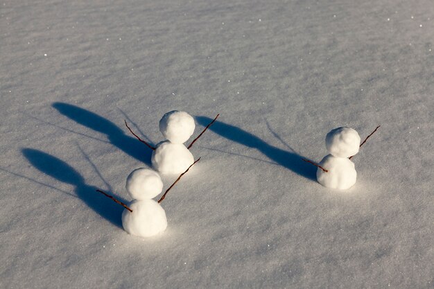 Três pequenos bonecos de neve na temporada de inverno, o boneco de neve é feito de várias partes e fica na neve no frio, jogos na neve com a criação de várias figuras de boneco de neve