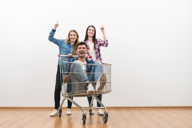 Foto las tres personas con un gesto de carrito de compras sobre un fondo de pared blanca