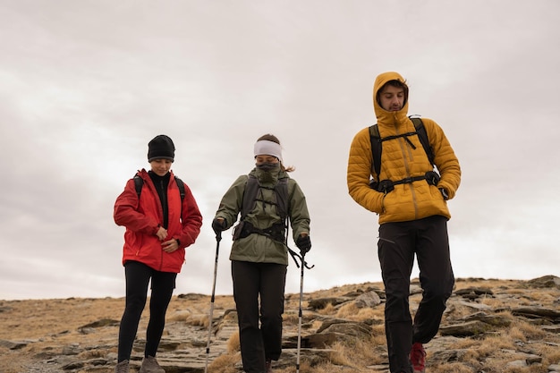 Foto tres personas haciendo senderismo en la montaña con mochilas a la espalda