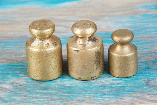 Três pesos de bronze antigos para escalas em fundo azul de madeira. Copie o espaço para adereços de fotografia de texto e comida.