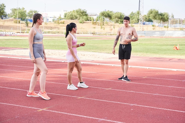 Três pessoas em pé na pista de atletismo