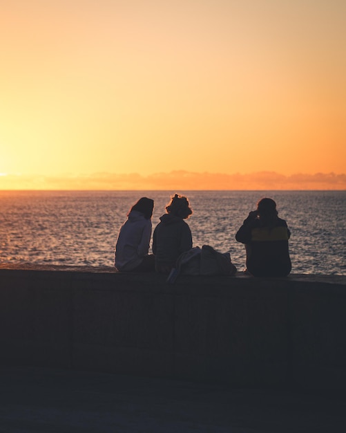 Três pessoas observando o precioso atardecer na costa de bajamar tenerife