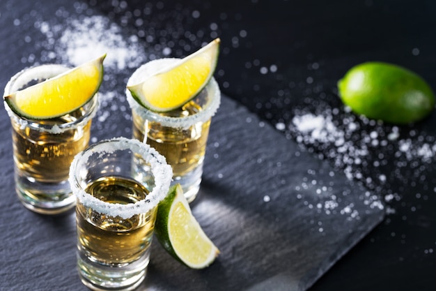 Três pilhas de tequila mexicana com limão e sal