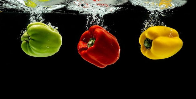 Três pimentas coloridas ou pimentas caindo na água