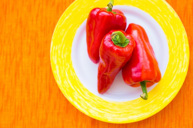 Tres pimientos rojos en un plato colorido closeup